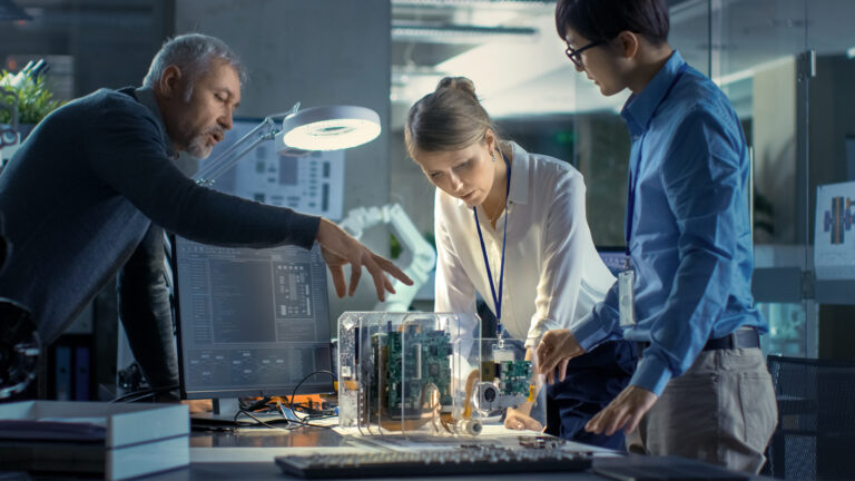 Researchers inspecting a newly designed prototype on a table.